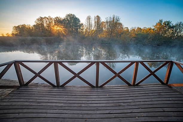 city ââautumn park by the river with fog.