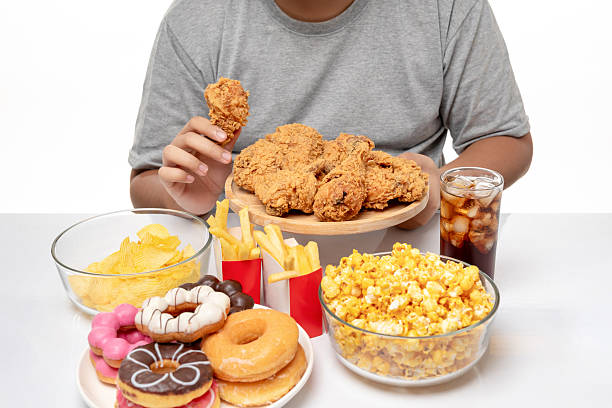 Cropped image of fat man eating fried chicken and unhealthy food, close-up, studio shot.