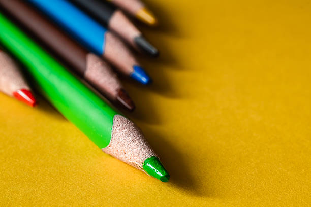 Texture colored pencils on a yellow background. Colored pencils close up.