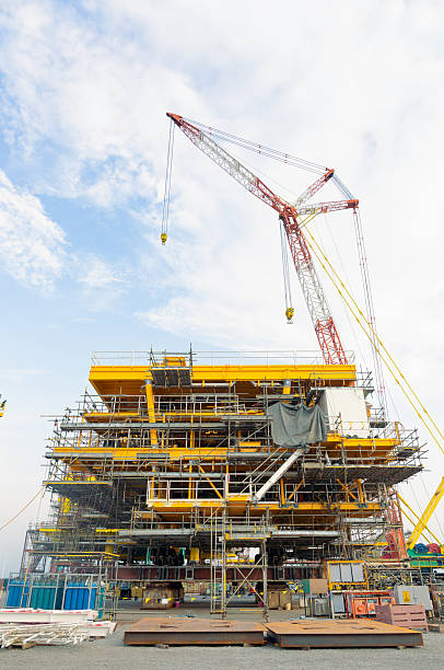 istock Large crane working in construction site to erect steel structure for oil rig platform. Industrial machine equipment for lifting heavy load in offshore drilling projects to explore natural resources. 2237481638