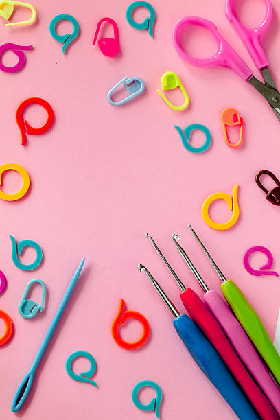 istock Bright crochet tools on a pink background. Crochet hooks, colored markers, needle and scissors. Copy space. 2237484879