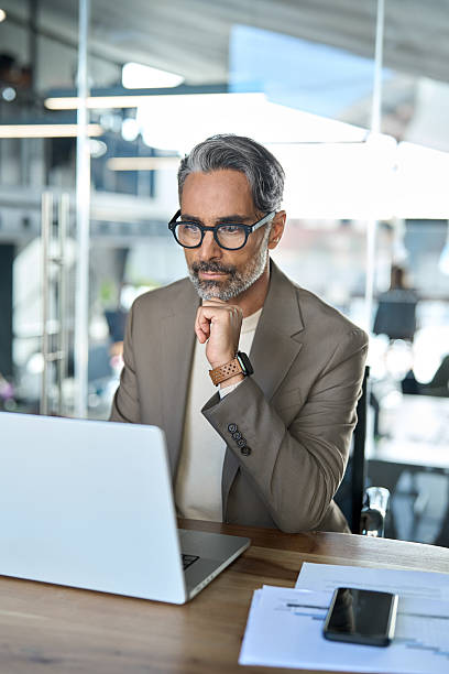 istock Serious busy mature business man executive sitting at desk using laptop. 2237489871
