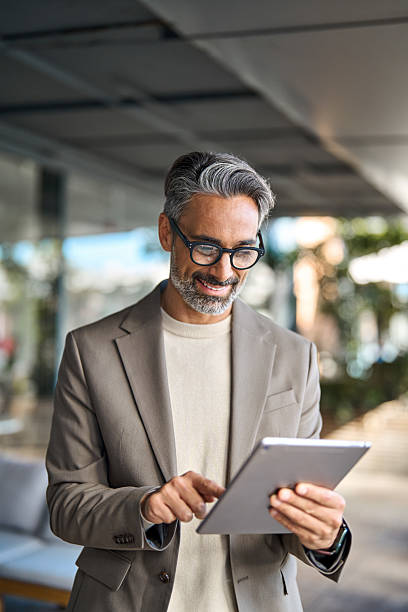 istock Busy happy older business man standing outdoors using digital tablet. Vertical. 2237489967