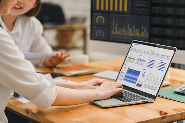 istock Businesswoman working on laptop with data analysis dashboard, discussing report with colleague in modern office, teamwork and collaboration concept 2237493977