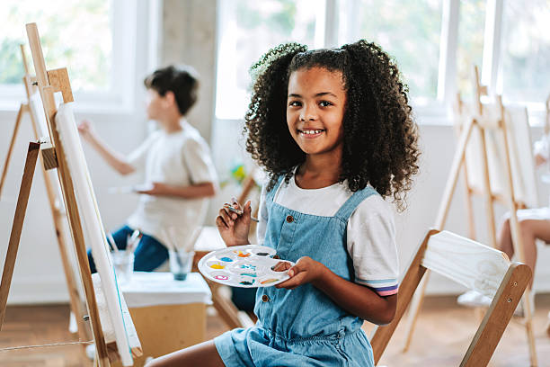 istock Black child girl looking at camera during painting class 2237495278