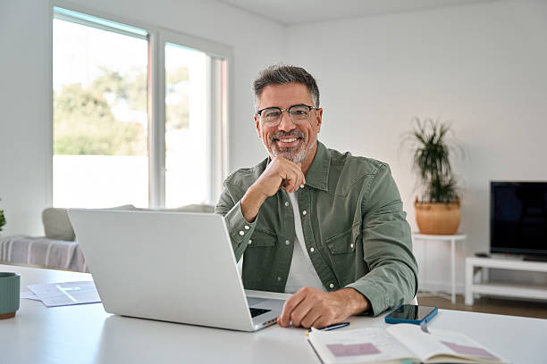 istock Happy older middle aged man using laptop computer at home table. Portrait 2237503404
