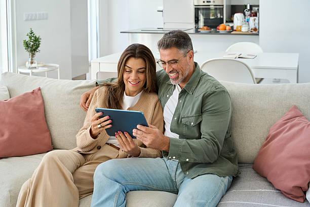 istock Happy middle aged couple using digital tablet relaxing on sofa at home. 2237503421