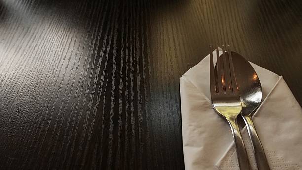 istock fork and spoon on white napkin, dark wooden table 2237507963