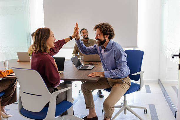 istock Business colleagues celebrating achievement with high five at boardroom table 2237508439