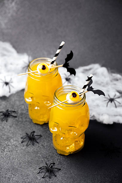 istock Two yellow drinks in skull jars with spider web and plastic spiders on dark background 2237512545