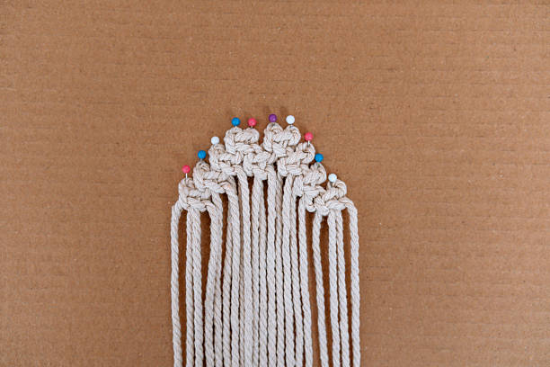 istock Round pinned macrame piece with colorful pins on cardboard background 2237512675