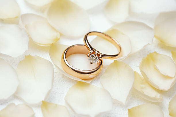 istock Wedding and engagement rings on white petals background 2237512691