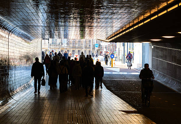 People walking in the train station tunnel towards the city and work in Amsterdam, the Netherlands.