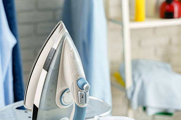 istock Steam iron on an ironing board next to fresh laundry in a bright laundry room 2237524211