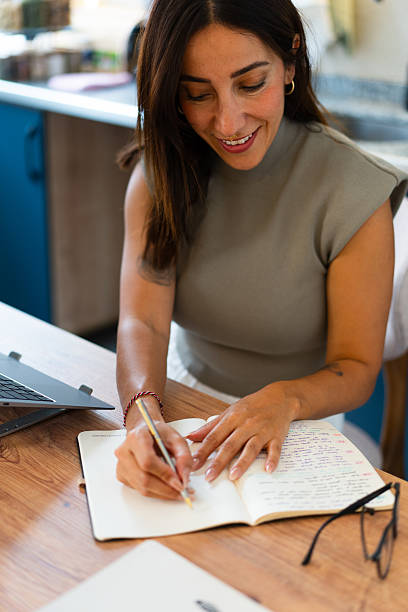 istock Woman smiling while writing notes in journal at home 2237524624