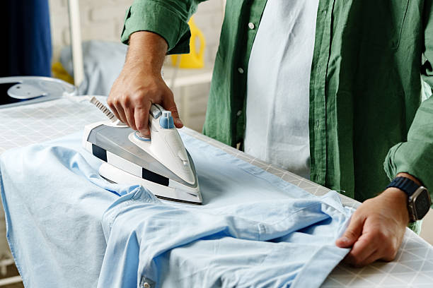 istock Ironing a blue shirt on an ironing board inside a well-lit laundry room 2237524684