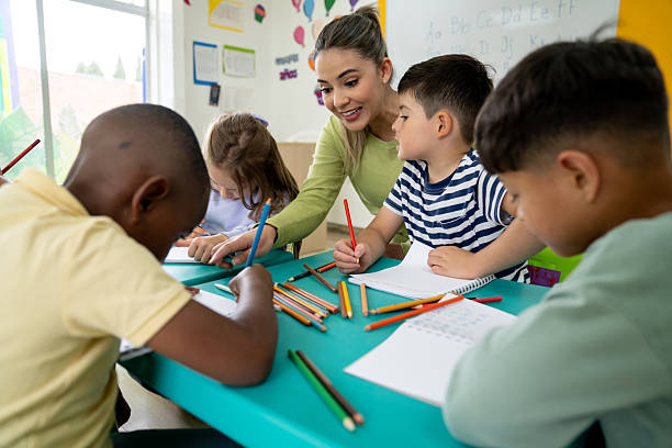istock Happy kindergarten teacher supervising children while they are drawing in class 2237526701