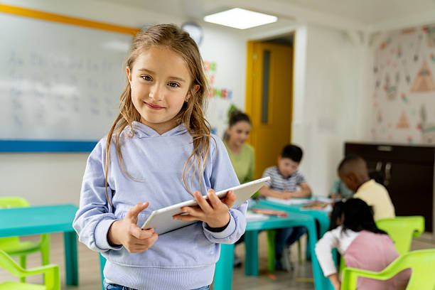 istock Happy girl holding a digital tablet while smiling at the kindergarten 2237526771