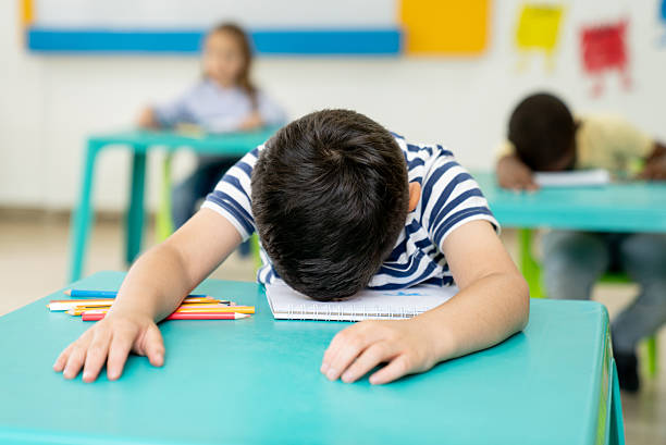 istock Tired schoolboy falling asleep on his desk in the classroom 2237526775