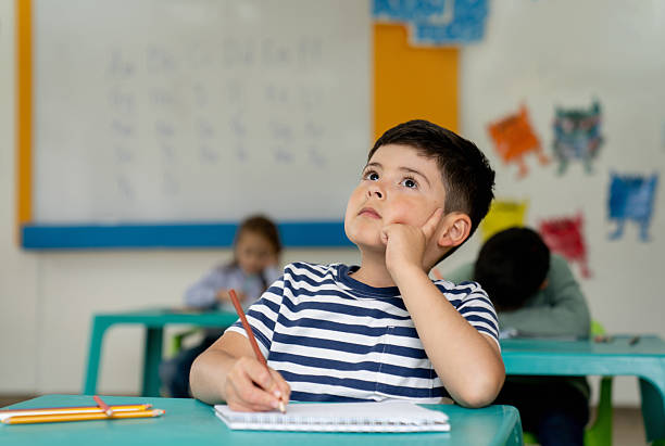 istock Thoughtful schoolboy at the school thinking of ideas while coloring 2237526781