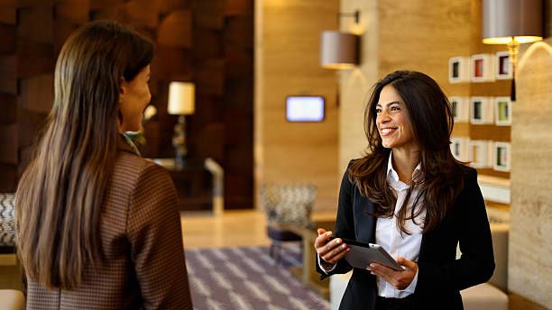 istock Smiling hotel staff member using a digital tablet while talking to a female guest in a modern hotel lobby 2237529256