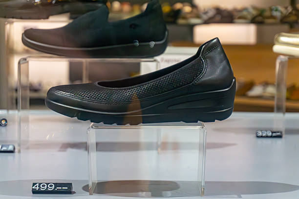 istock Black leather women’s shoe with low wedge heel displayed on a transparent store shelf. 2237534811