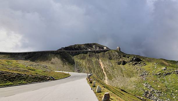 A scenic view of a winding mountain road under a dramatic sky in Grossglockner, Austria, showcasing natural beauty and adventure.