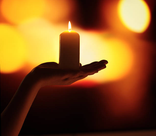 istock Hands holding burning candle in dark. Selective soft focus, blur smoke black, red, yellow background. 2237536694