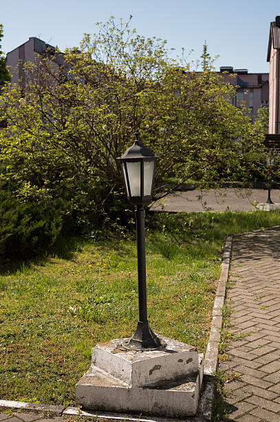 istock Outdoor black lamp post in garden with greenery and pathway 2237541562