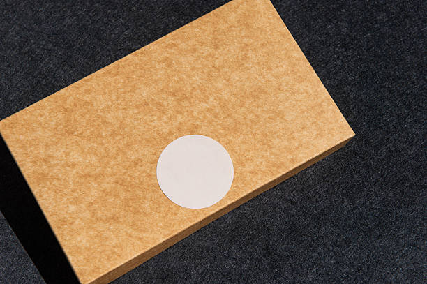 istock Brown box with white sticker on dark surface in sunlight 2237541573
