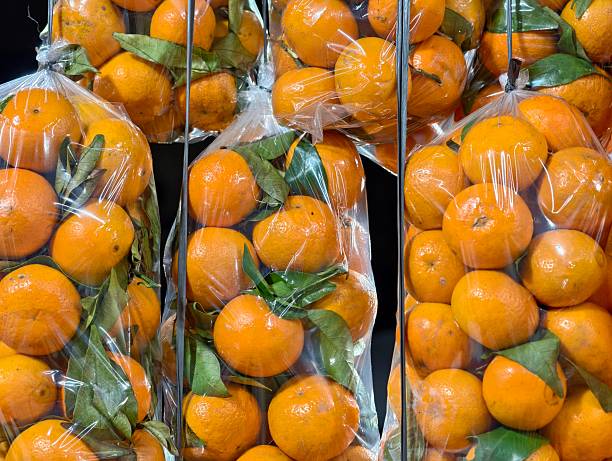 Bags of ripe, juicy oranges with green leaves, ready for sale at a market.