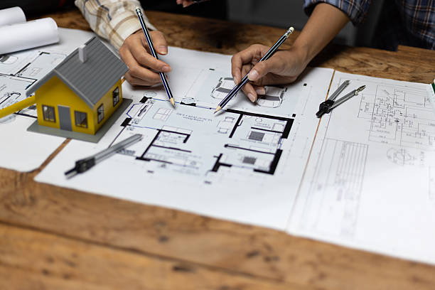 istock Collaboration female architects brainstorming discuss construction project design blueprints on wooden table in dark office. Colleagues are planning and calculating the budget for house construction. 2237543136