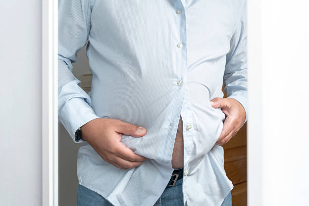 istock Man struggling with tight shirt showing weight gain 2237544908