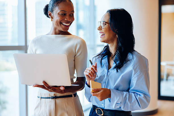 istock Two professional women discussing work while smiling in an office environment 2237546304