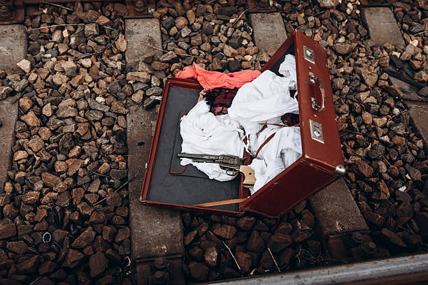 Open suitcase on railway tracks with clothes and gun
