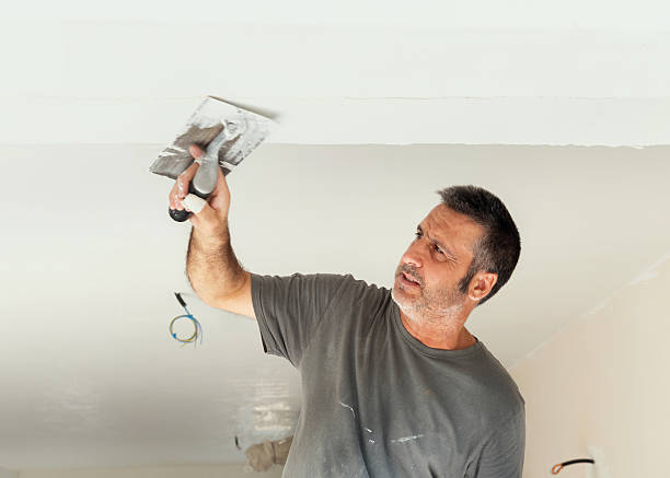 istock Man in grey work t-shirt uses trowel and hawk to plaster ceiling, construction or renovation of house 2237558766