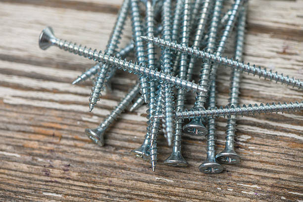 istock Shiny screws on wooden table 2237560036