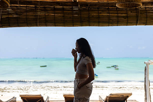 istock woman drinking coffee in front of the beach 2237560045