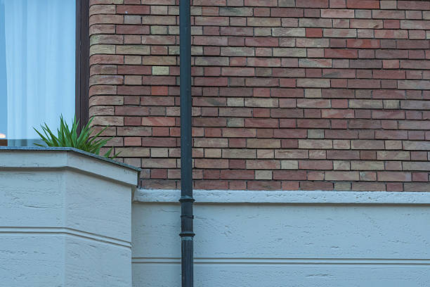Close-up on an old brick wall with a white plastic pipe