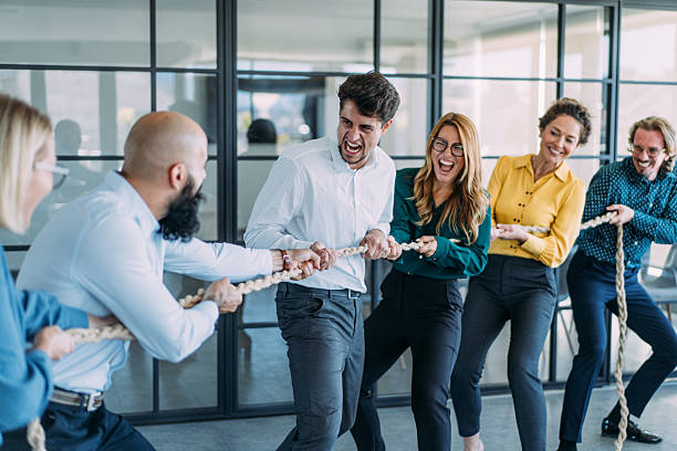istock Playful colleagues having fun while playing tug-of-war in the office. 2237568325
