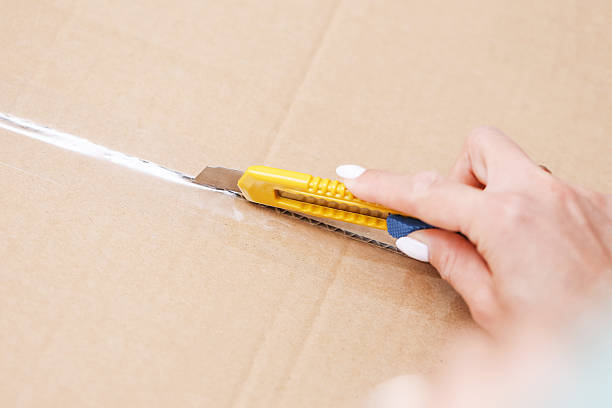 istock Hand cutting cardboard box with utility knife. Person opening package with sharp blade tool. Home delivery unboxing scene. 2237568680