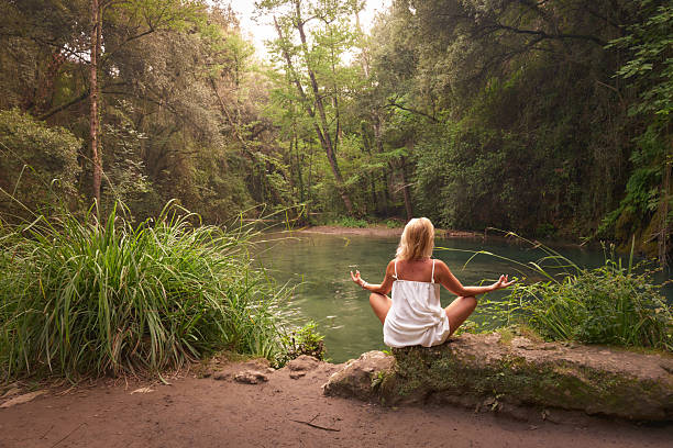 Woman focusing on wellness and solitude practicing yoga in nature.