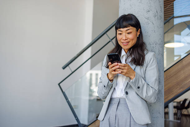 istock Asian businesswoman smiling using smartphone in modern office 2237576328