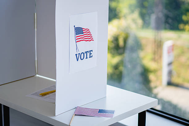Voting booth with vote sign and American flag at polling place, symbolizing civic duty, privacy and US Democratic process