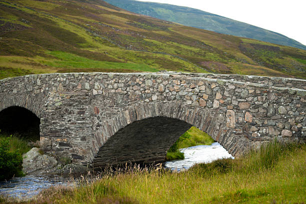 A beautiful stone arched bridge above small river , view from rural Scottish village