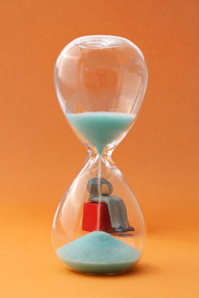 istock Executive lets time pass by sitting behind an hourglass 2237585823