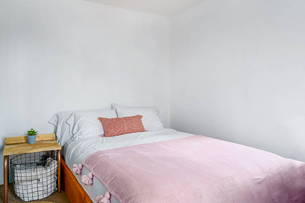 istock Bedroom white, pink chenille pillow, throw blanket, side table basket 2237586534