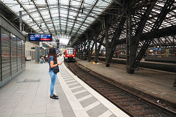 Middle Aged Woman Waiting on Platform for Commuting by Train and Traveling on Public Transportation and Infrastructure - Cologne Germany
