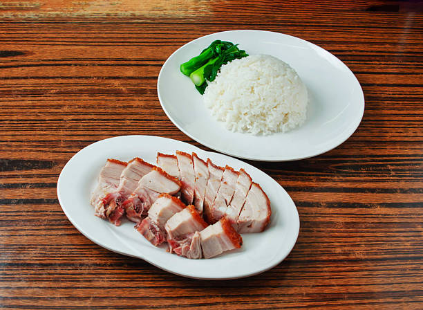Crispy Skin Chinese Roast Pork Belly Siu Yuk with Steamed Rice and Choy Sum in white platter on wooden board side view of main course