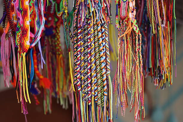 Collection of colorful handmade friendship bracelets, crafted with braided and knotted threads in various bright patterns. The vibrant mix of colors — red, yellow, blue, green, and purple — creates a lively and festive display, with loose strands hanging at the ends.